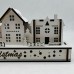 White Wood Christmas Light up Decoration Featuring a Village Scene With Tree and Houses. Laser Cut Wood is Hand Assembled With LED Lights. UK